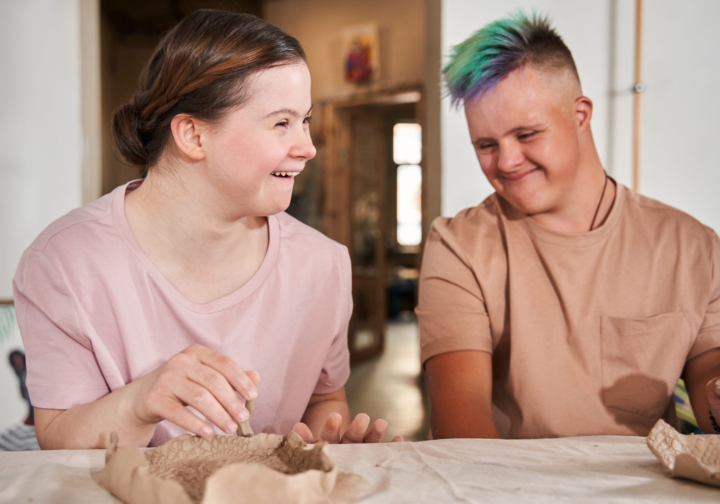 Thank you for the master class. Portrait view of the happy girl with down syndrome laughing out loud and looking away while enjoying of the pottery lesson